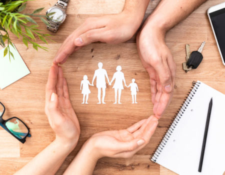 Family care concept. Hands with paper silhouette on table.