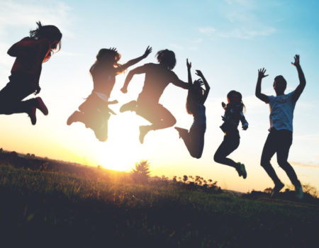 Group of people jumping outdoors; sunset